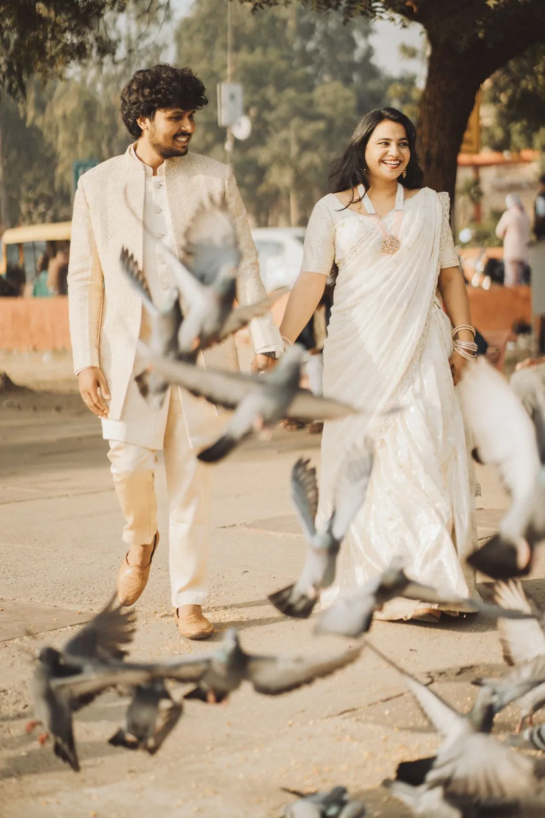 Couple laughing as pigeons fly around them during a Jaipur pre-wedding shoot