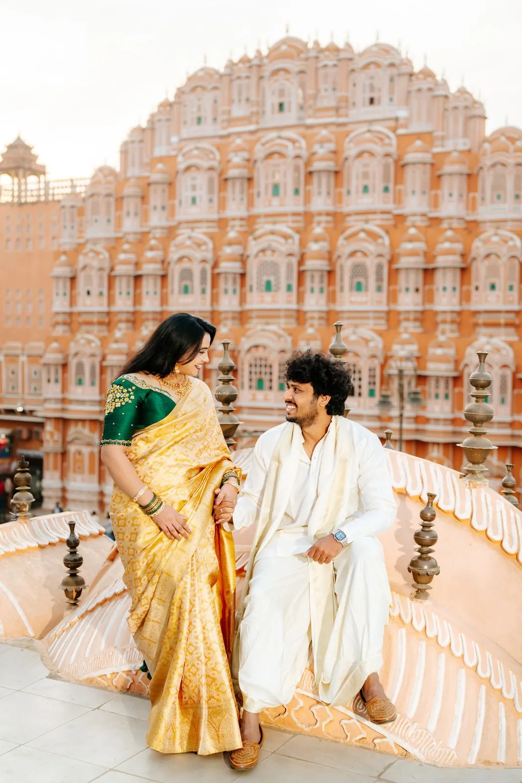 Couple in traditional outfits in front of the pink facade of Hawa Mahal