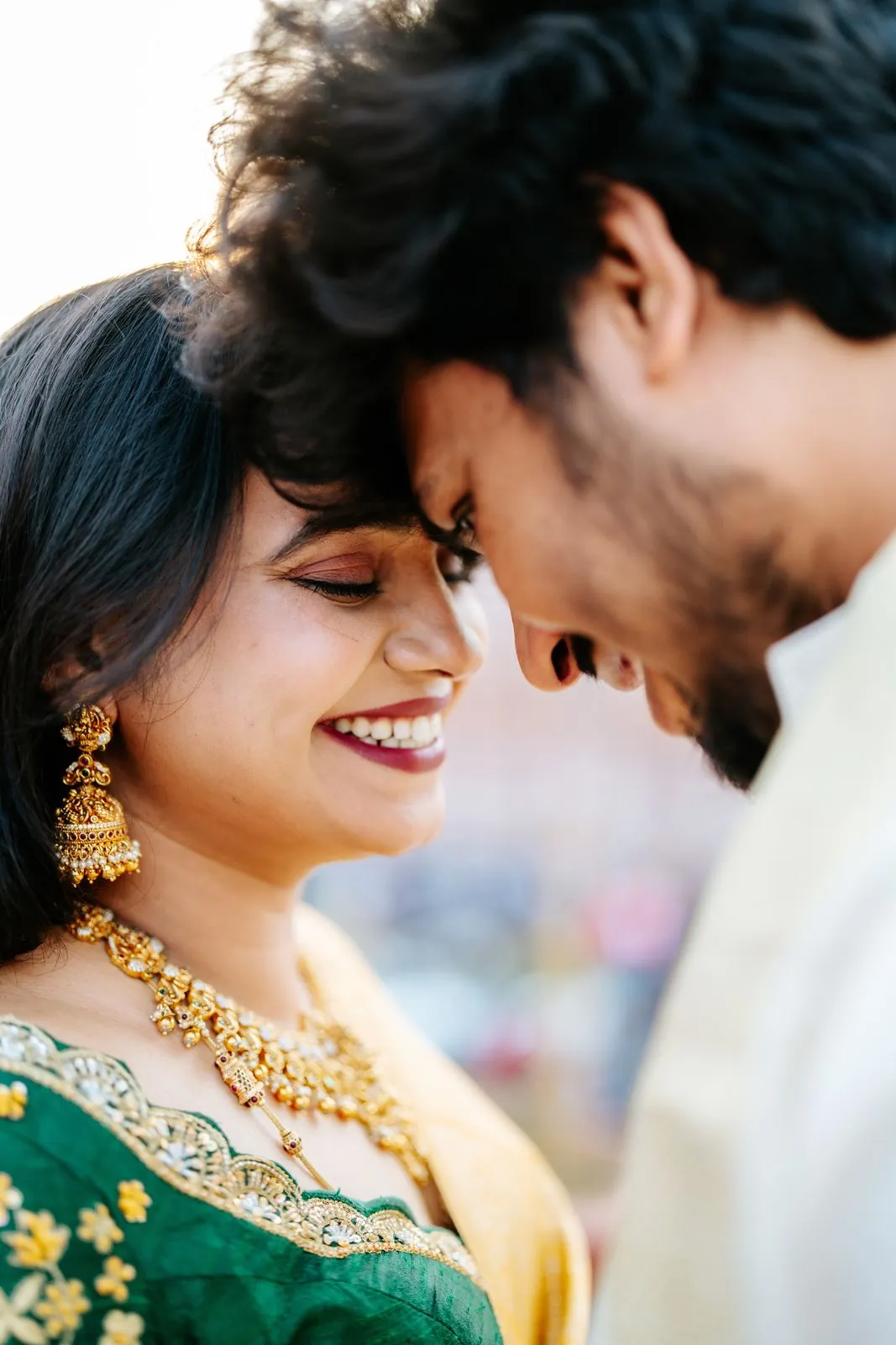 Close portrait of a bride in a green and gold saree with her partner