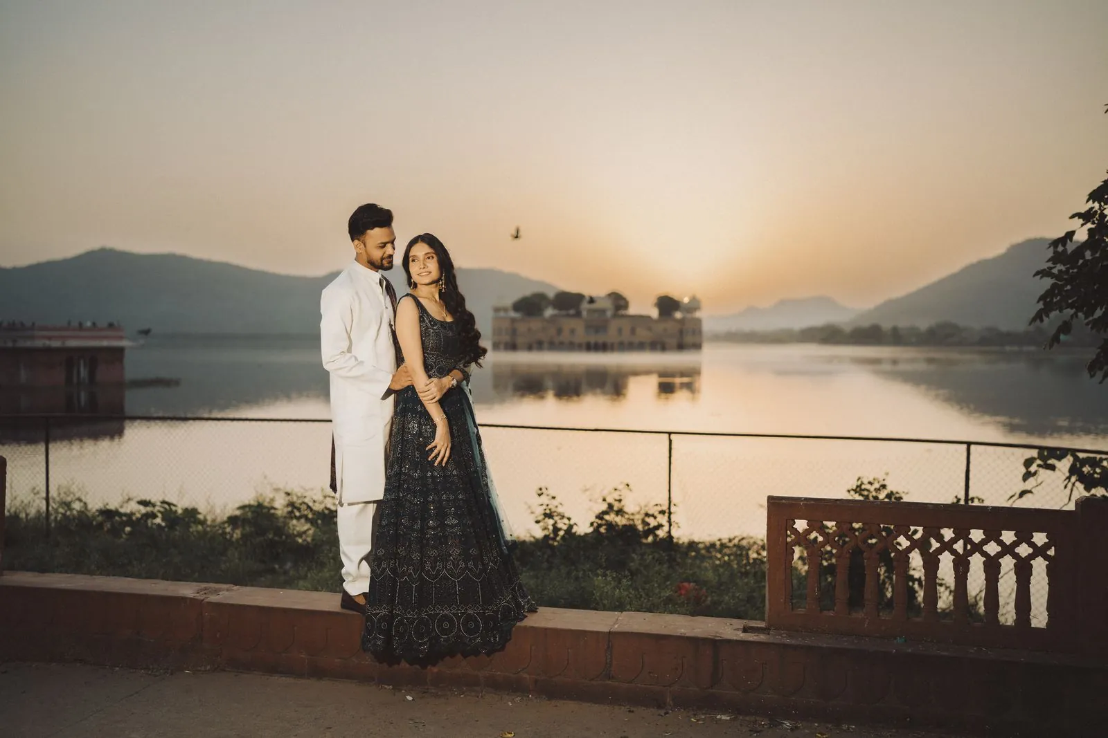 Couple at sunrise beside Man Sagar Lake with Jal Mahal in the distance