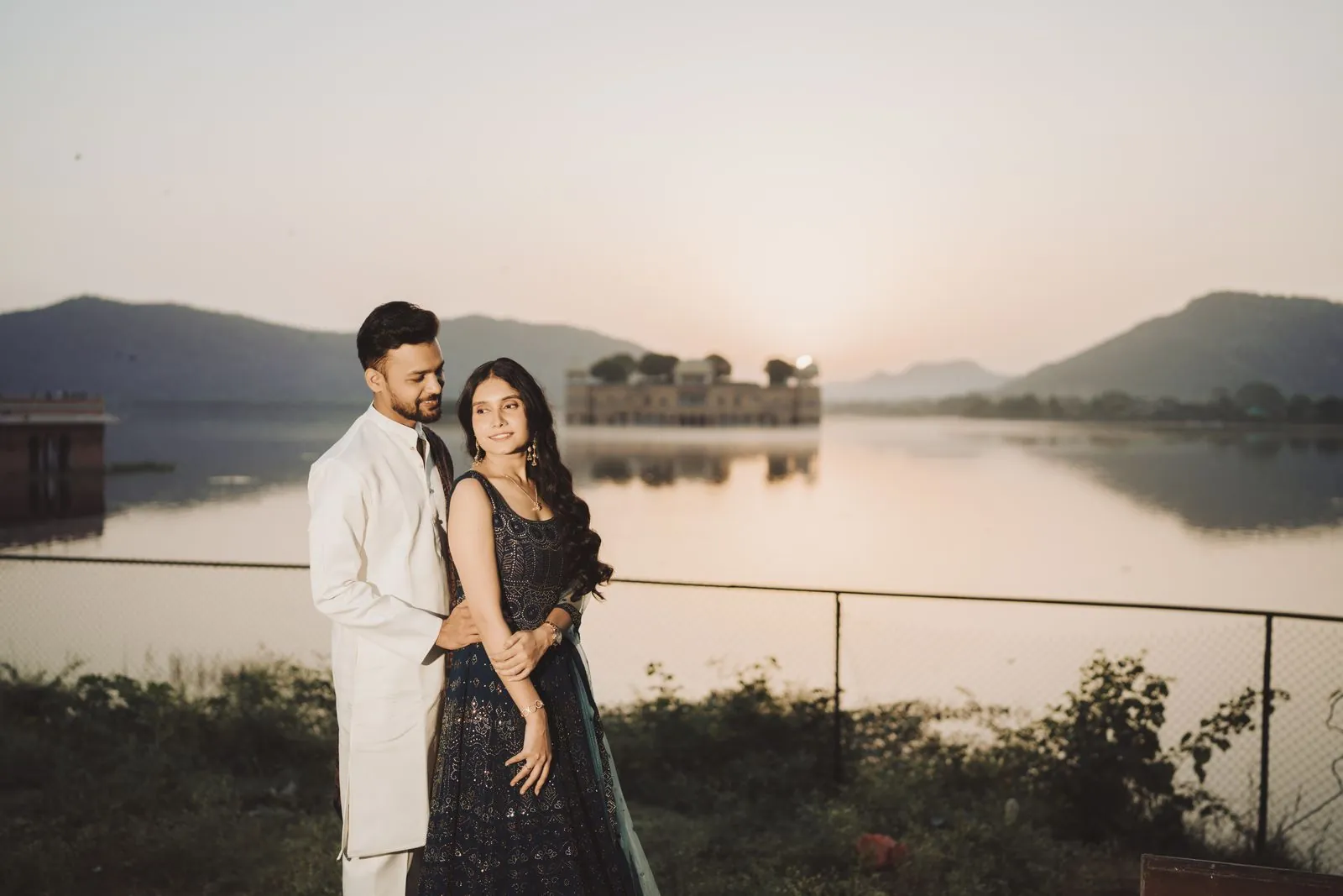Couple at sunrise on the Jal Mahal promenade with the lake and palace behind them