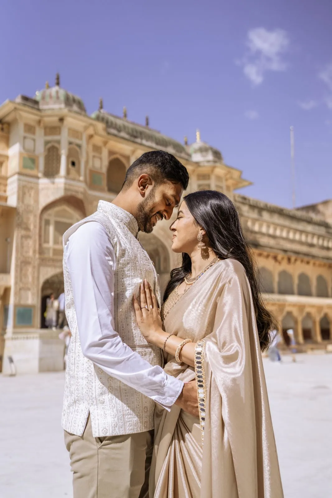 Couple in a courtyard at Amer Fort with the palace walls behind them