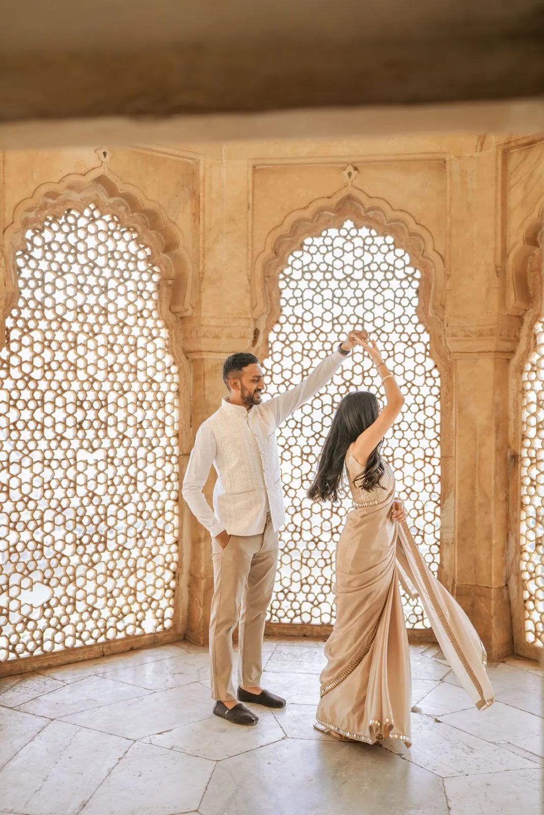 Bride twirling in a saree beside jali windows at Amer Fort, Jaipur